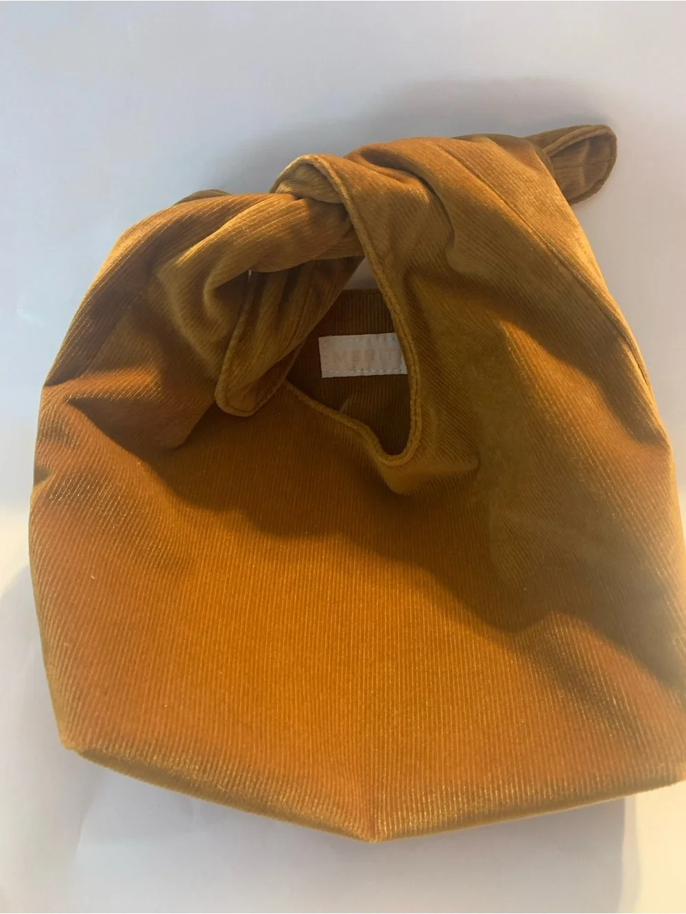 Merit Beauty Signature Bag in a golden brown or camel corduroy material